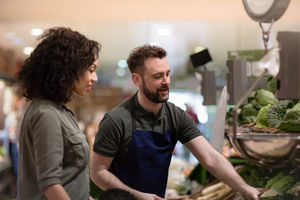 Shop assistant in grocery store helping shopper