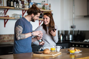 Young couple looking at smartphone together over breakfast