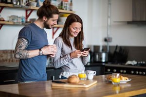 Young couple looking at smartphone together over breakfast