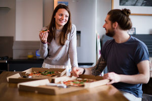 Young couple eating takeout pizza at home