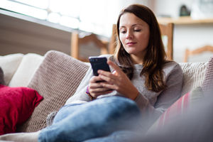 Young adult female on sofa using smartphone