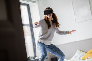 Young adult female learning to surf with VR headset