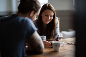 Young adult couple in a cafŽ together looking at a smartphone