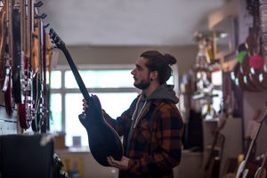 Young adult male looking at guitar in shop