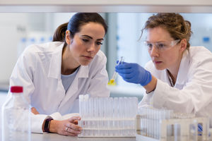 Two female scientists analyzing test tube sample