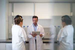 Team of scientists discussing experiment data on digital tablet