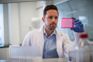 Male scientist looking at microplate in a laboratory