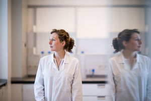 Female scientist looking out of window with reflection