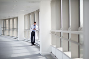 Male medical professional using smartphone in corridor