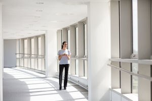Businesswoman holding smartphone looking out of window in office