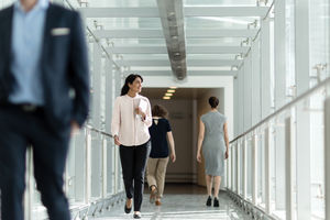 Female business executive walking through busy office corridor
