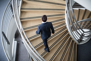 Businessman walking up spiral staircase in office