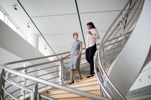 Female business colleagues walking down spiral staircase