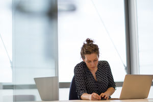 Female executive syncing smartphone to laptop