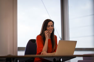 Female executive working on laptop and using smartphone