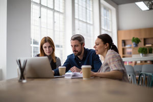 Coworkers looking at a laptop in a meeting