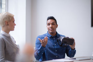 Designer presenting virtual reality headset in a meeting