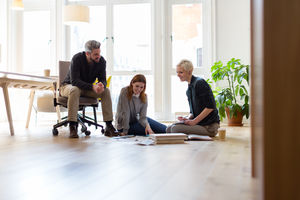 Group of designers discussing ideas with paperwork on office floor