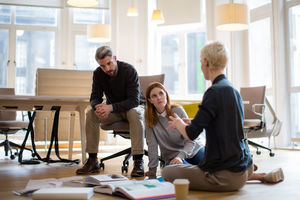 Group of designers discussing ideas with paperwork on office floor