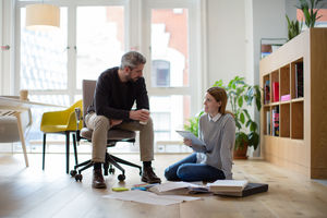 Colleagues discussing ideas with paperwork on office floor