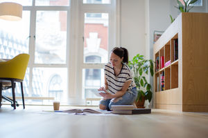 Female designer working on ideas with digital tablet and paperwork on office floor