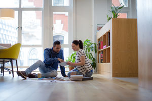 Colleagues working on ideas with digital tablet and paperwork on office floor