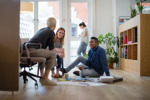 Colleagues discussing ideas with paperwork on office floor