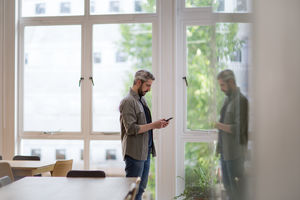Businessman in empty office looking at smartphone