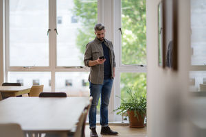 Businessman in empty office looking at smartphone