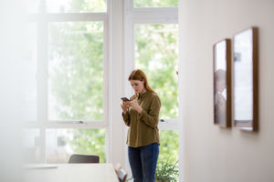 Businesswoman in empty office looking at smartphone