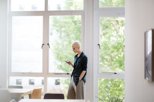 Businesswoman in empty office looking at smartphone