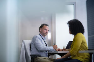 Male Medical Doctor taking notes of patient symptoms