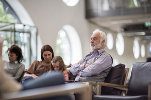 Senior Male waiting in a crowded hospital waiting room 