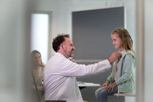 Male Medical Doctor listening to childs heartbeat