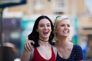 Female friends walking down a street of shops in summer