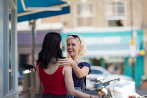 Female friends meeting outdoors on shopping street