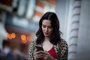 Young adult female using smartphone on street