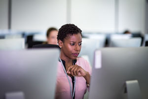 Businesswoman using computer in crowded office