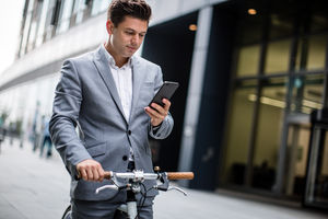 Businessman cycling to work using smartphone