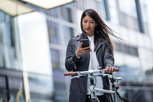 Businesswoman cycling to work using smartphone