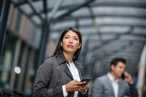Businesswoman waiting for train on platform with smartphone in hand
