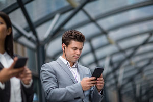 Businessman listening to podcast waiting for train at station