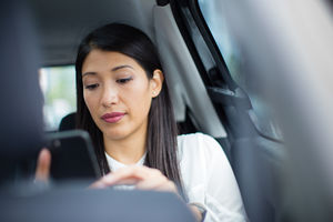 Businesswoman in taxi cab using smartphone