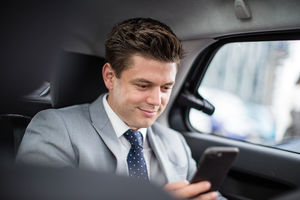 Businessman in taxi cab using smartphone