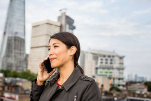 Businesswoman using smartphone with London city skyline