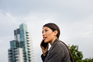 Businesswoman using smartphone with skyscraper in background