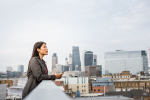 Businesswoman looking out at London city skyline