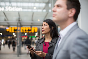 Commuter looking at train times at station holding smartphone