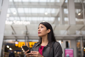 Commuter looking at train times at station holding smartphone