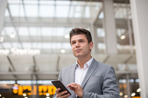 Commuter looking at train times at station holding smartphone